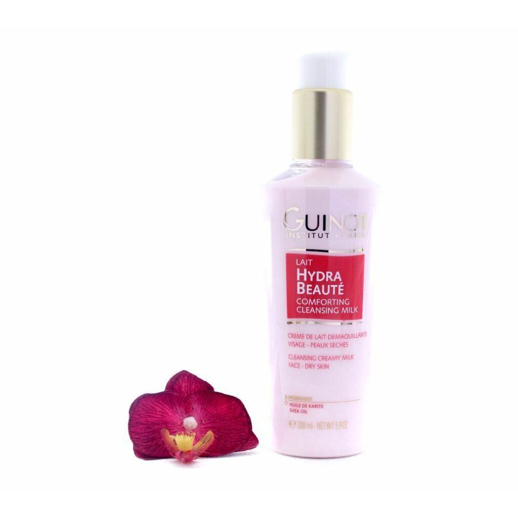 Flacone rosa con tappo dorato. Scritta: Guinot, Lait Hydra Beauté, Cleansing Milk. Un'orchidea è accanto.