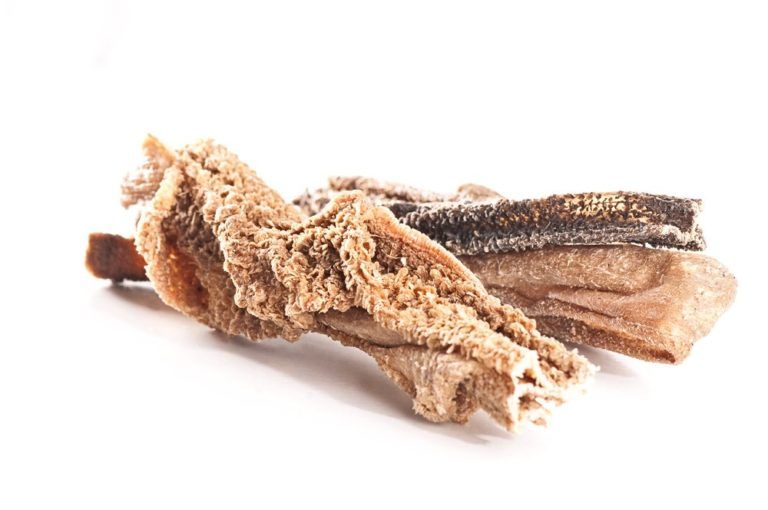 Pezzi di trippa di agnello, marroni e beige, su sfondo bianco. Texture ruvide e lisce.