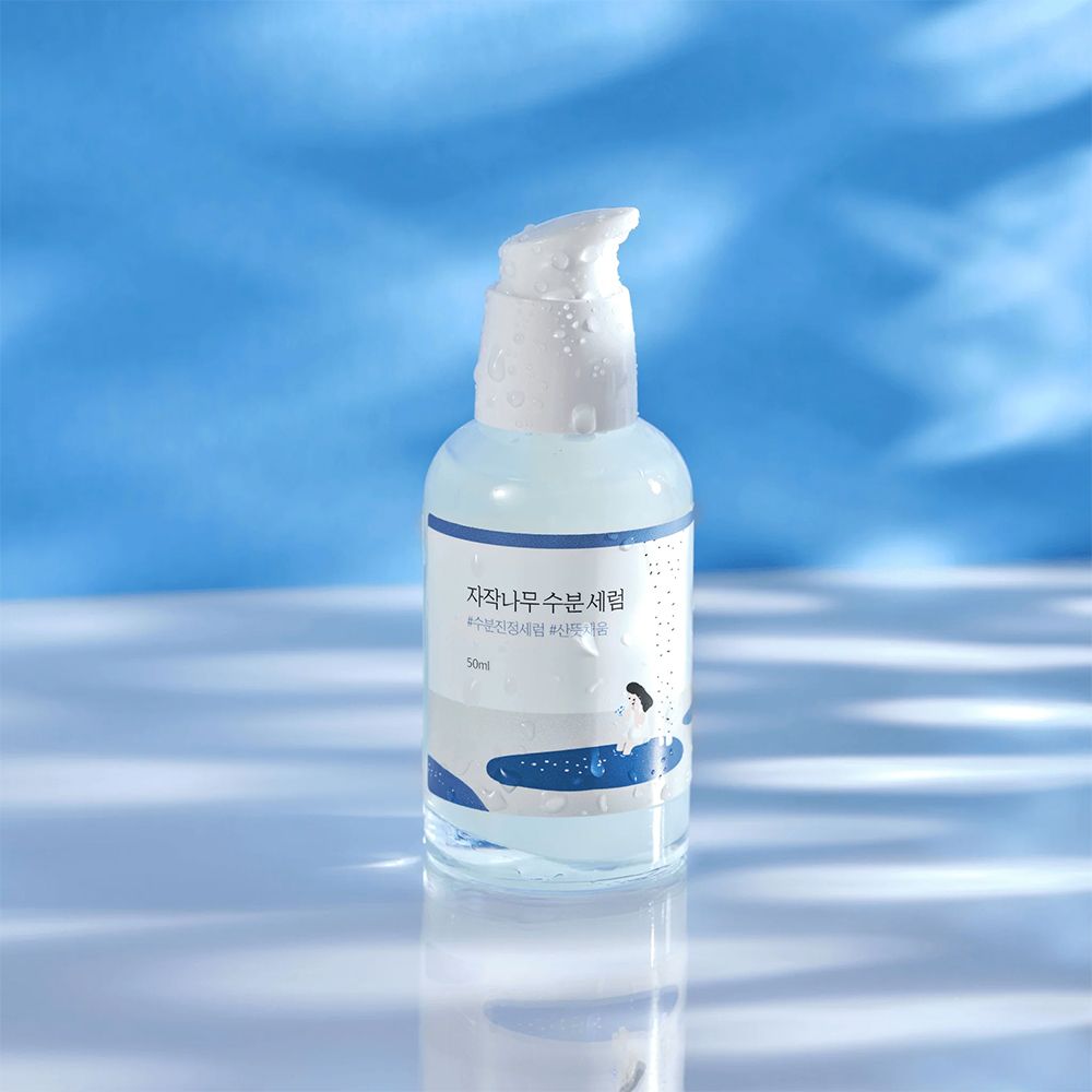 Round Lab Birch Juice Serum, 50ml, in flacone con erogatore su sfondo blu con riflessi di luce.