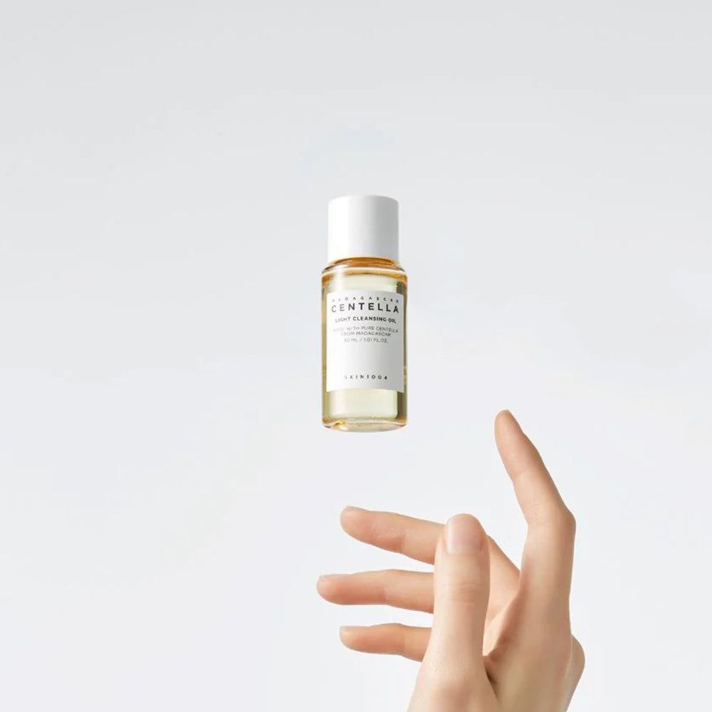 Flacone di olio trasparente con tappo bianco. Mano che cerca di afferrare il flacone.