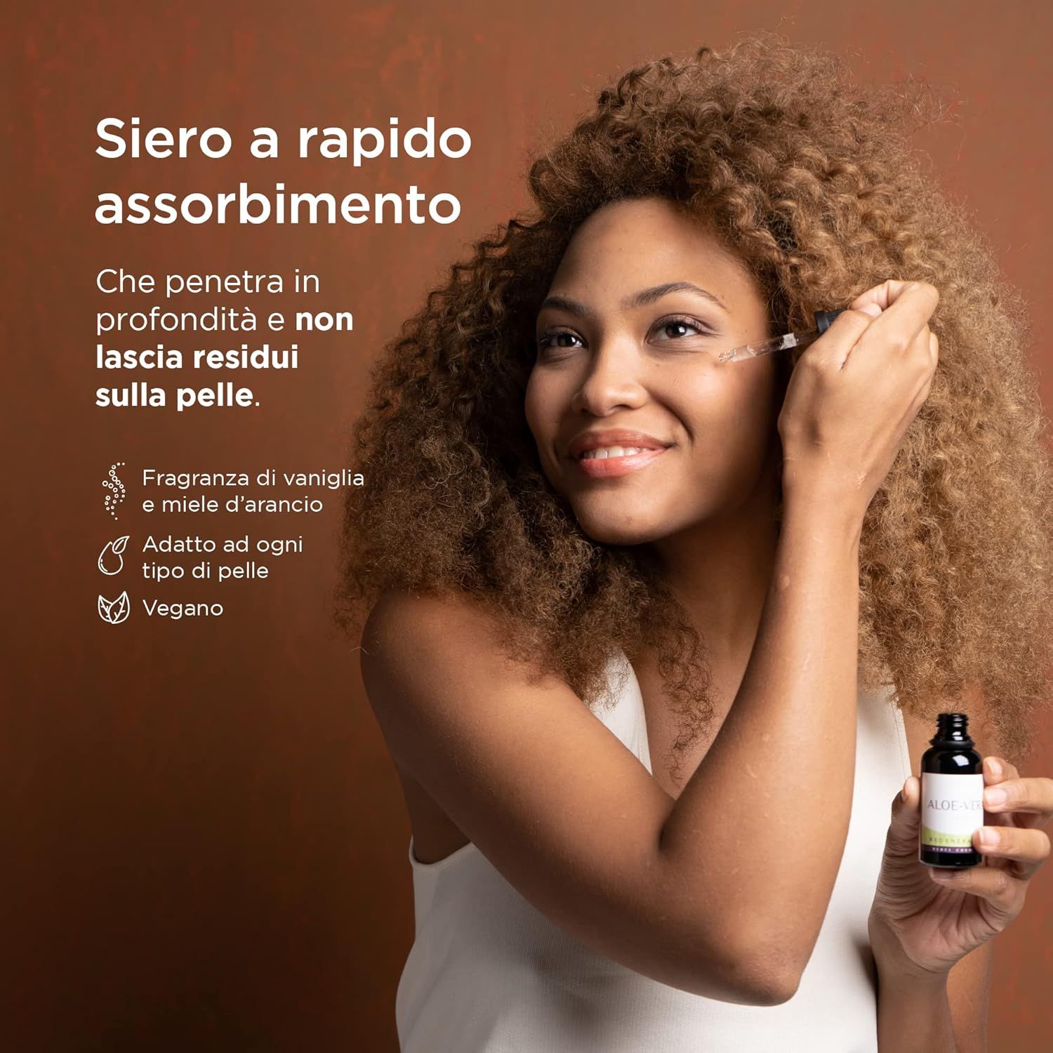 Donna con ricci che applica il siero. Flacone in mano. Testo: Siero ad assorbimento rapido. Adatto a tutti i tipi di pelle. Vegano.