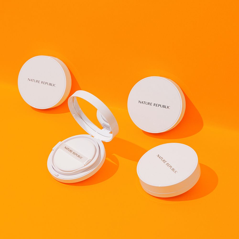 Diversi contenitori rotondi bianchi su sfondo arancione. Alcuni aperti, con spugne e specchi. Marchio visibile.