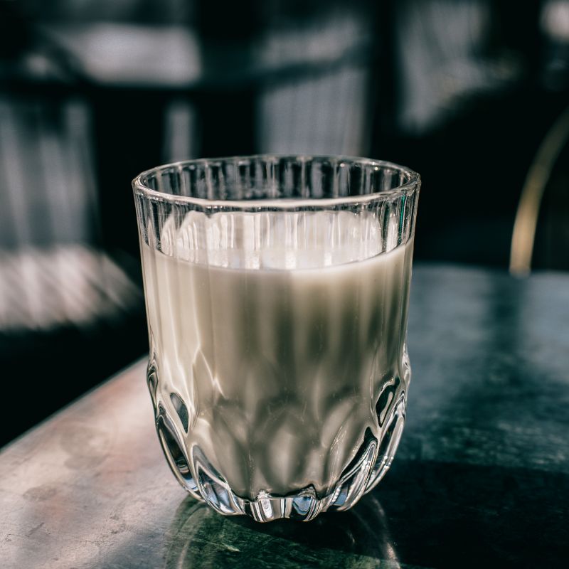 Bicchiere con liquido lattiginoso. Vetro trasparente con design scanalato, su una superficie.