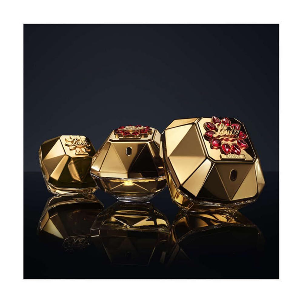 Tre flaconi dorati a forma di diamante. Quello centrale ha un coperchio rosso.