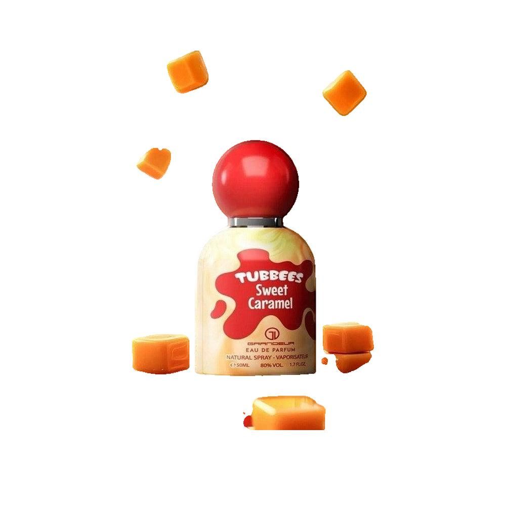 Flacone di profumo con tappo rosso e scritta. Scritta: TUBBEES Sweet Caramel. Circondato da cubetti di caramello.