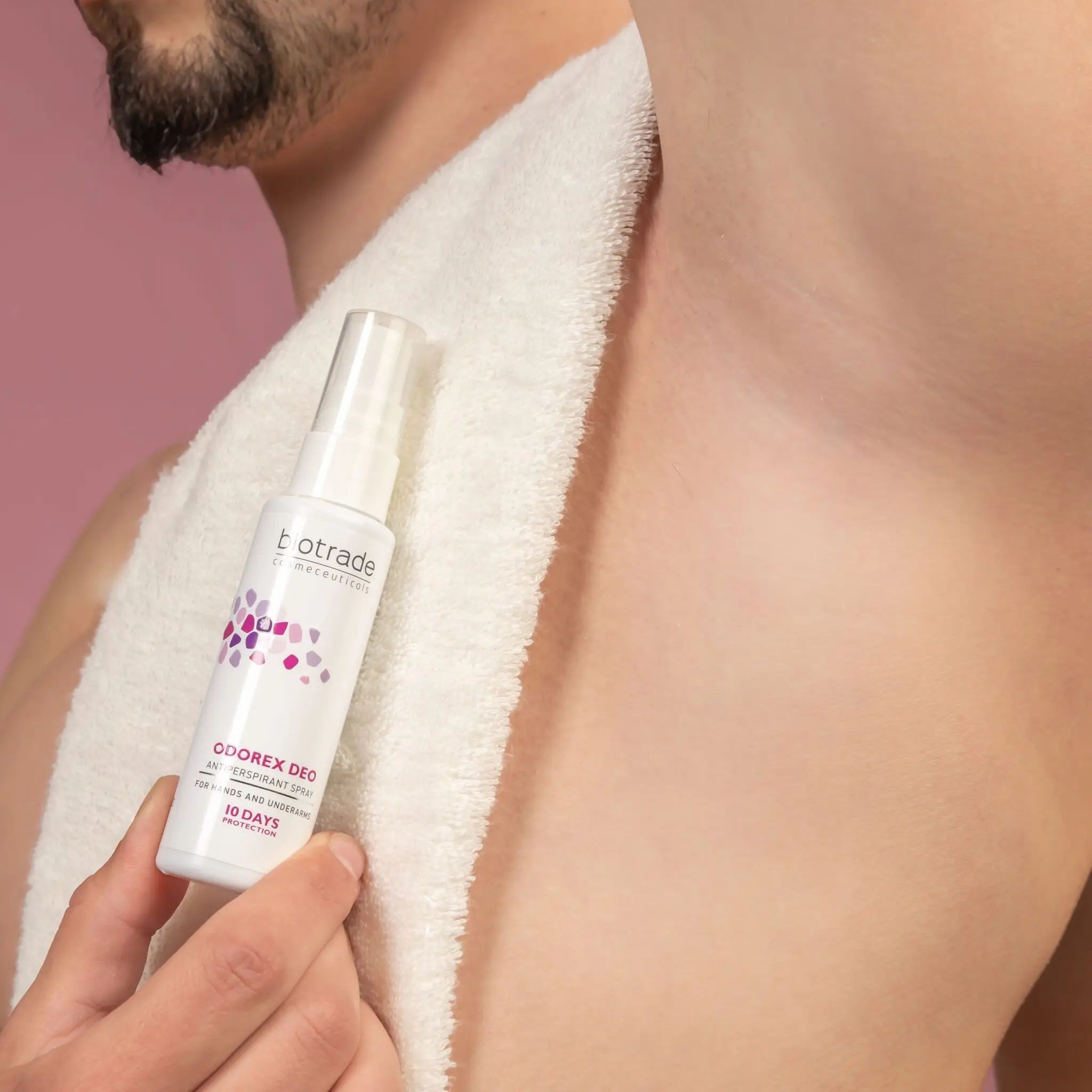 Persona tiene flacone spray bianco. Scritta: Biotrade, Odorex Deo, spray antitraspirante. Protezione 10 giorni. Braccio sotto asciugamano.