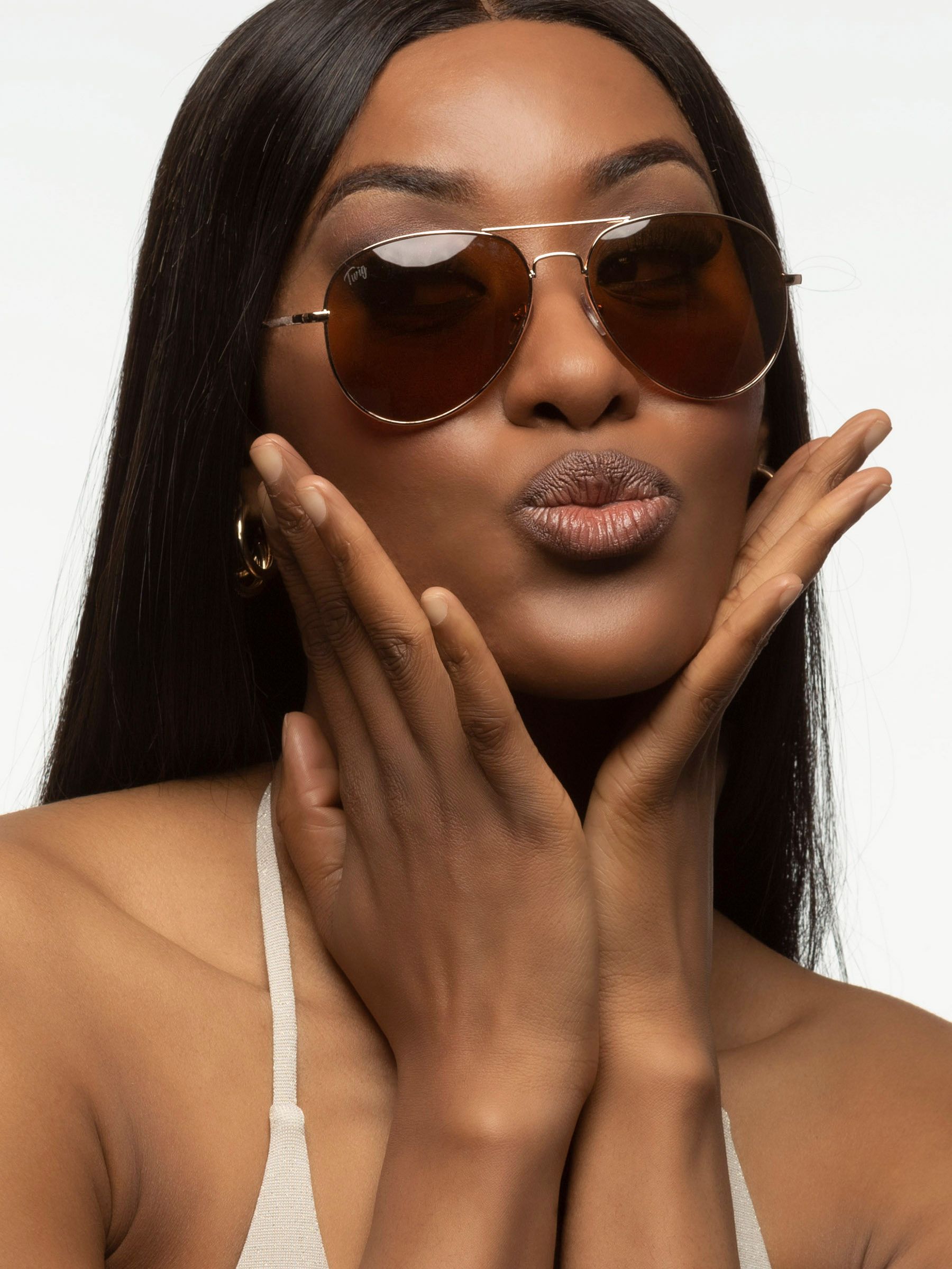 Donna con occhiali da sole Twig. Montatura dorata, lenti marroni. Primo piano.
