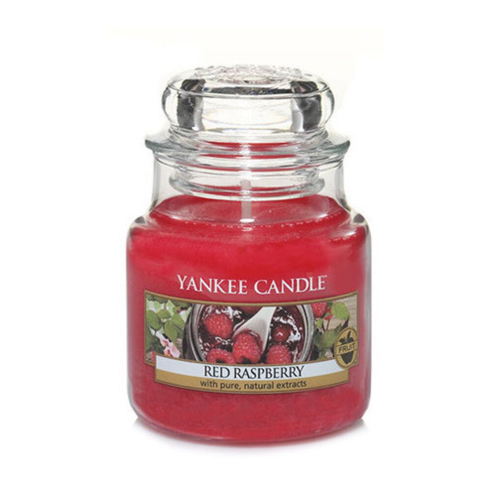 Candela rossa in barattolo con coperchio. Scritta: Yankee Candle Red Raspberry. Immagine di lamponi.