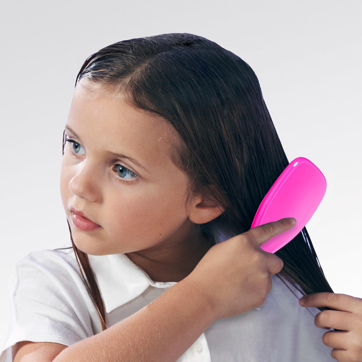 Bambina che si pettina i capelli con una spazzola rosa.