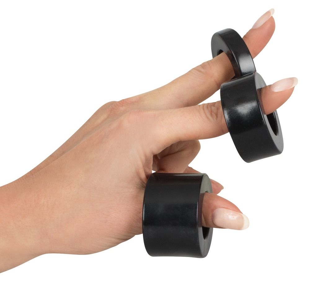 Mano con tre anelli neri sulle dita. Anelli cilindrici.