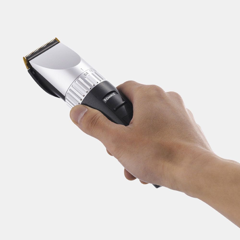 Mano che tiene la tosatrice. Corpo nero, testa argentata. Marca: Panasonic ER1512.