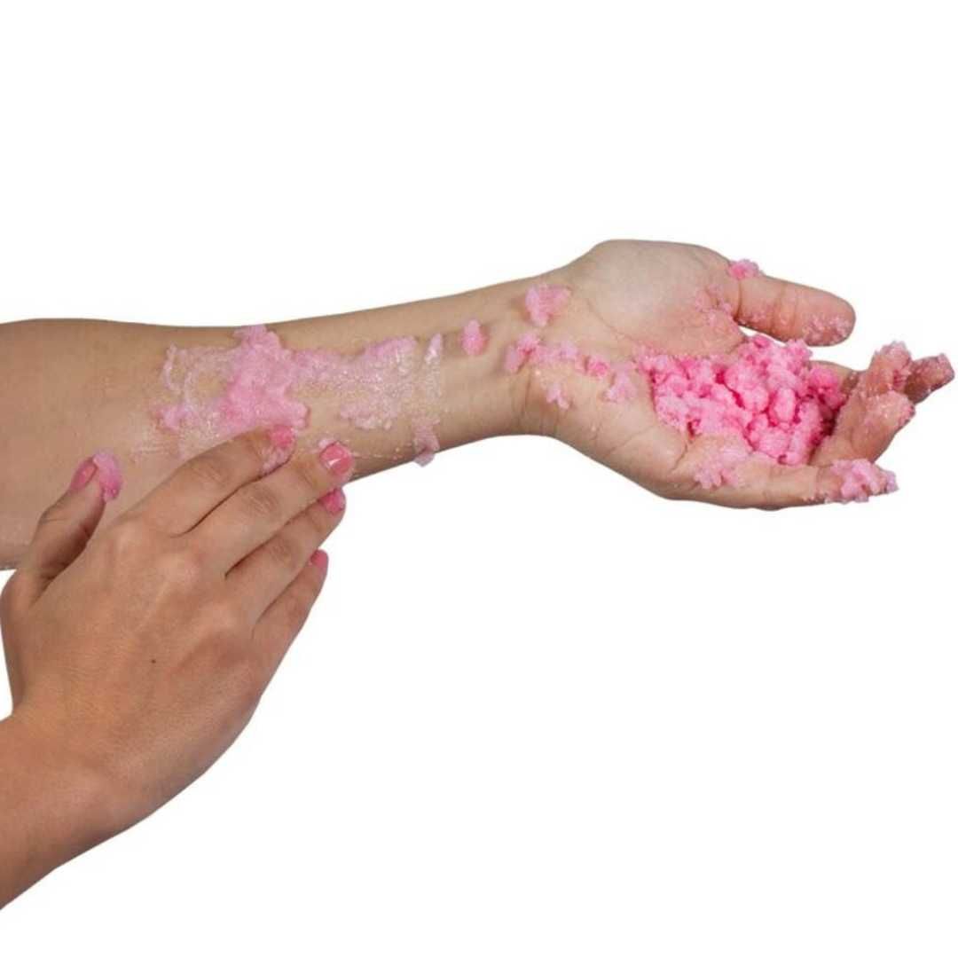 Mani con sale da bagno rosa sul braccio. Prodotto in forma granulare.