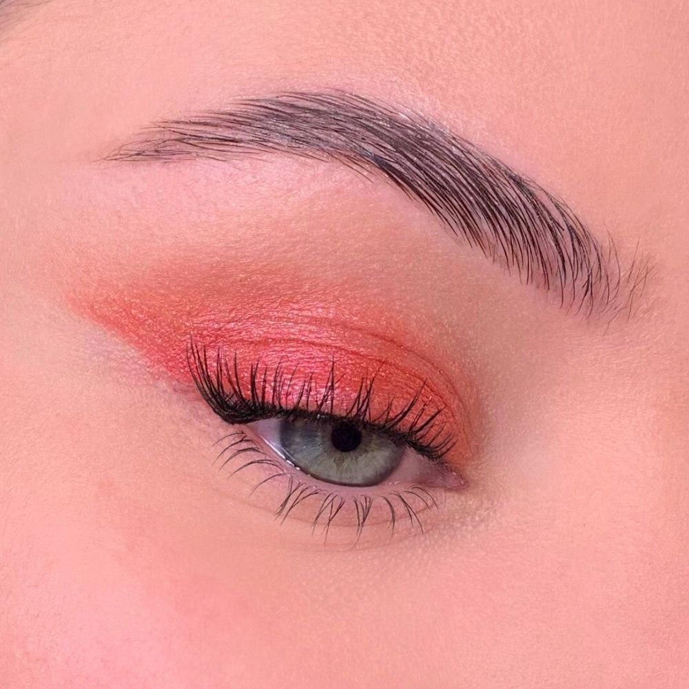 Occhio con ombretto rosso. Palpebra superiore ricoperta di ombretto rosso. Ciglia e sopracciglia visibili.