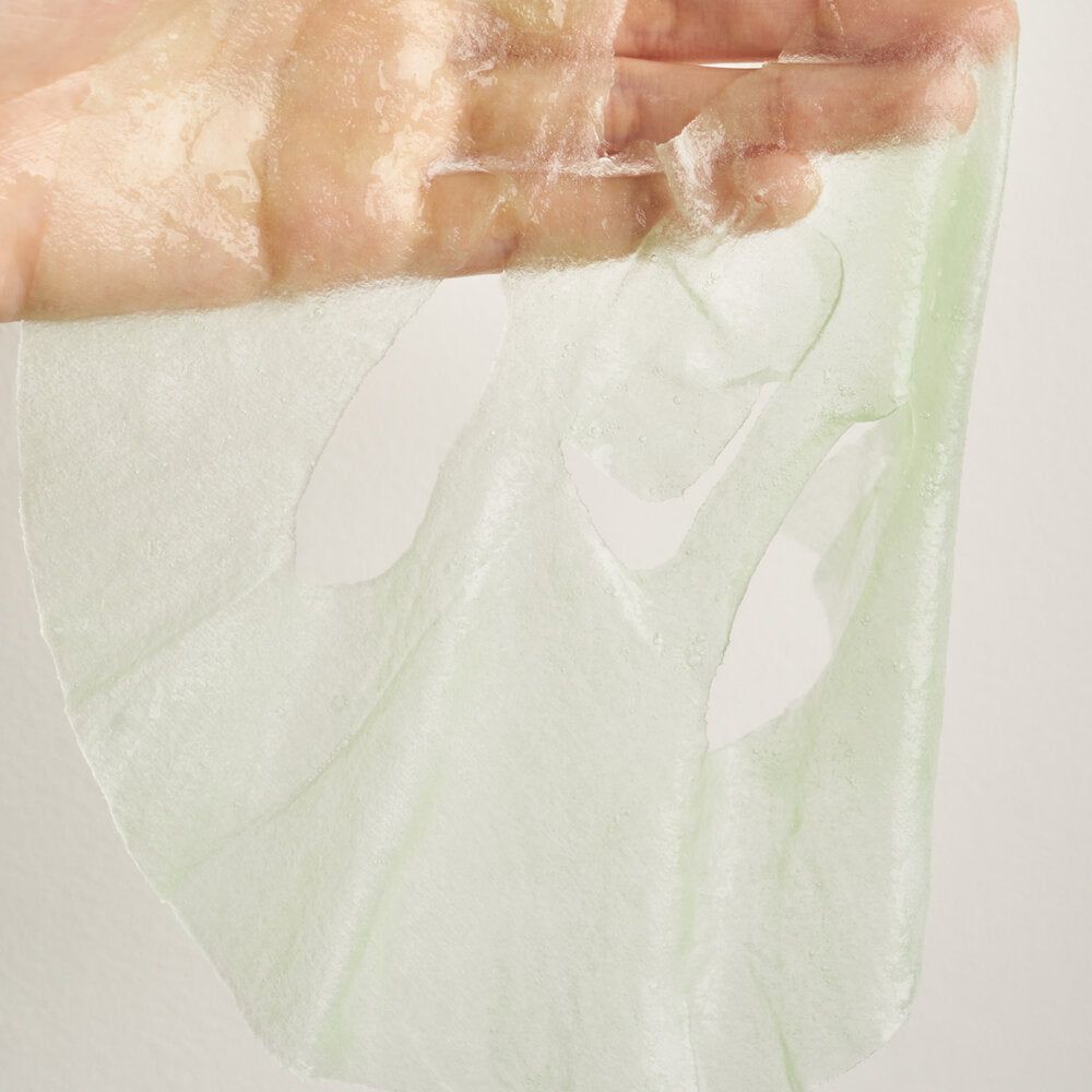 Maschera viso verde in una mano. La maschera ha fori per occhi e bocca. È trasparente e umida.