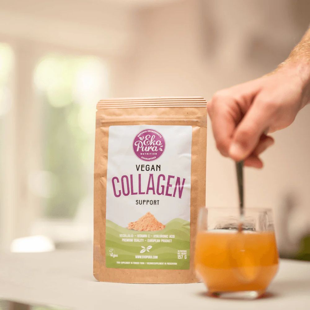 Busta Vegan Collagen Support. Cucchiaio che mescola in un bicchiere. Mano che tiene il cucchiaio. Sfondo: cucina.