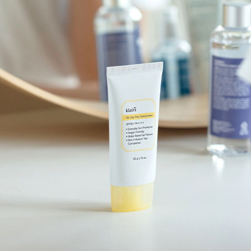 Tubo bianco con tappo giallo su un tavolo. Scritta: klairs, All-day Airy Sunscreen, SPF50+ PA++++, 50 g.