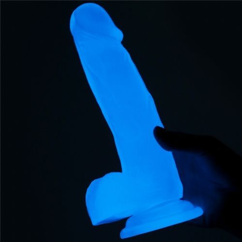 Dildo blu brillante in ambiente scuro. Mano che tocca il giocattolo.