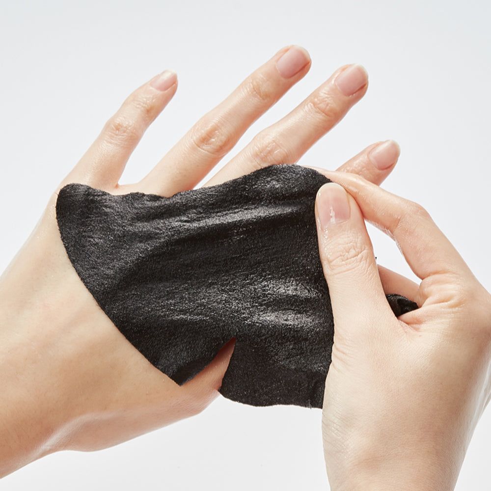 Mani che tengono una maschera per il viso nera. La maschera è fatta di materiale nero e leggermente umido.