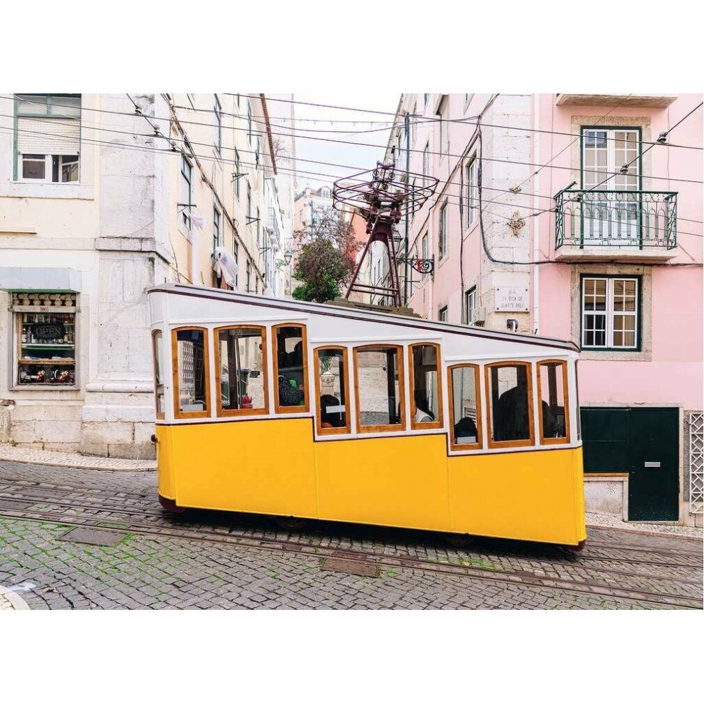 Tram giallo su ciottoli davanti alle case. Finestre con cornice in legno. Catenaria visibile.