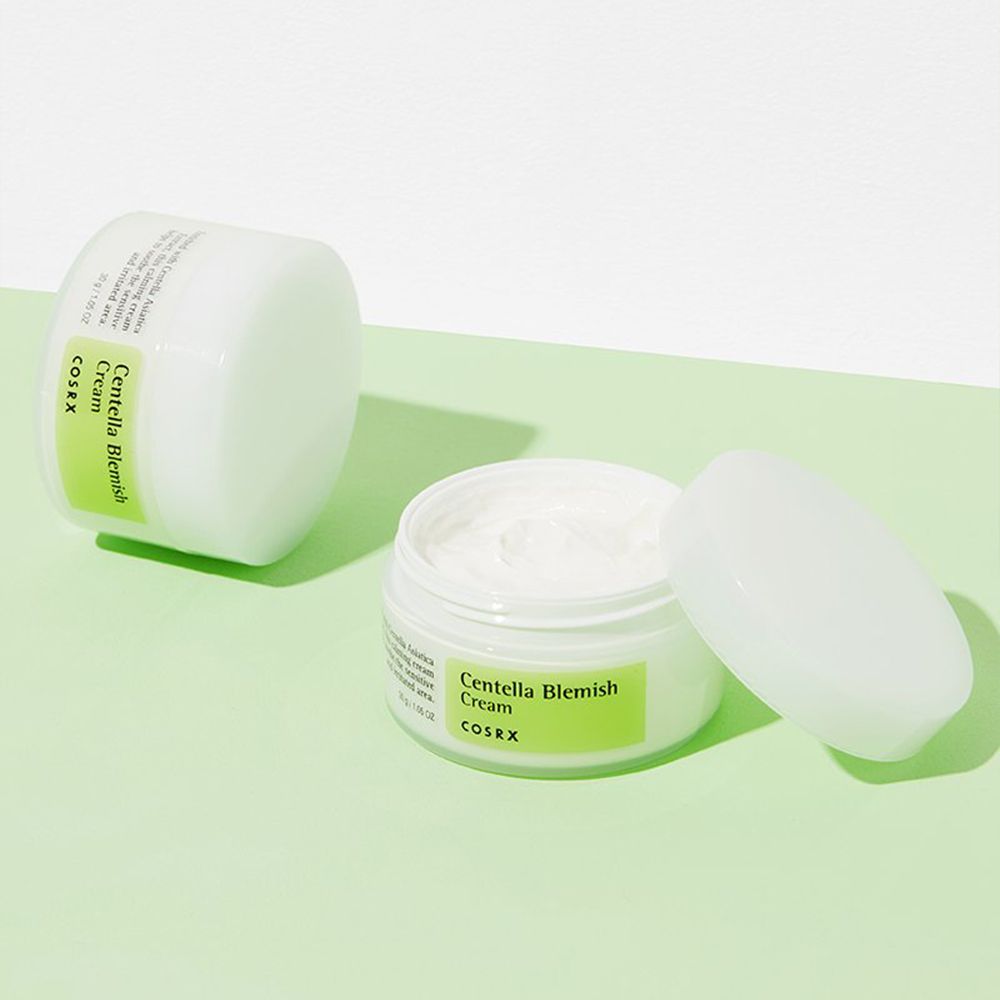 Due vasetti di crema COSRX Centella Blemish, uno aperto, su sfondo verde.