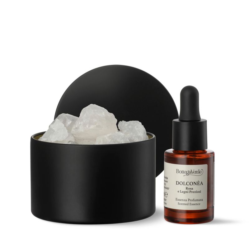Contenitore nero con cristalli di quarzo, accanto bottiglia con etichetta: Dolconèa, Rosa e Legni Preziosi. Contagocce.
