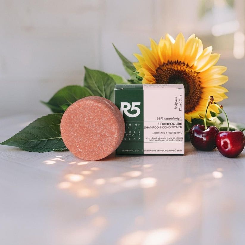 Shampoo solido rotondo e confezione. Su superficie in legno con girasole e ciliegie. Confezione con testo.