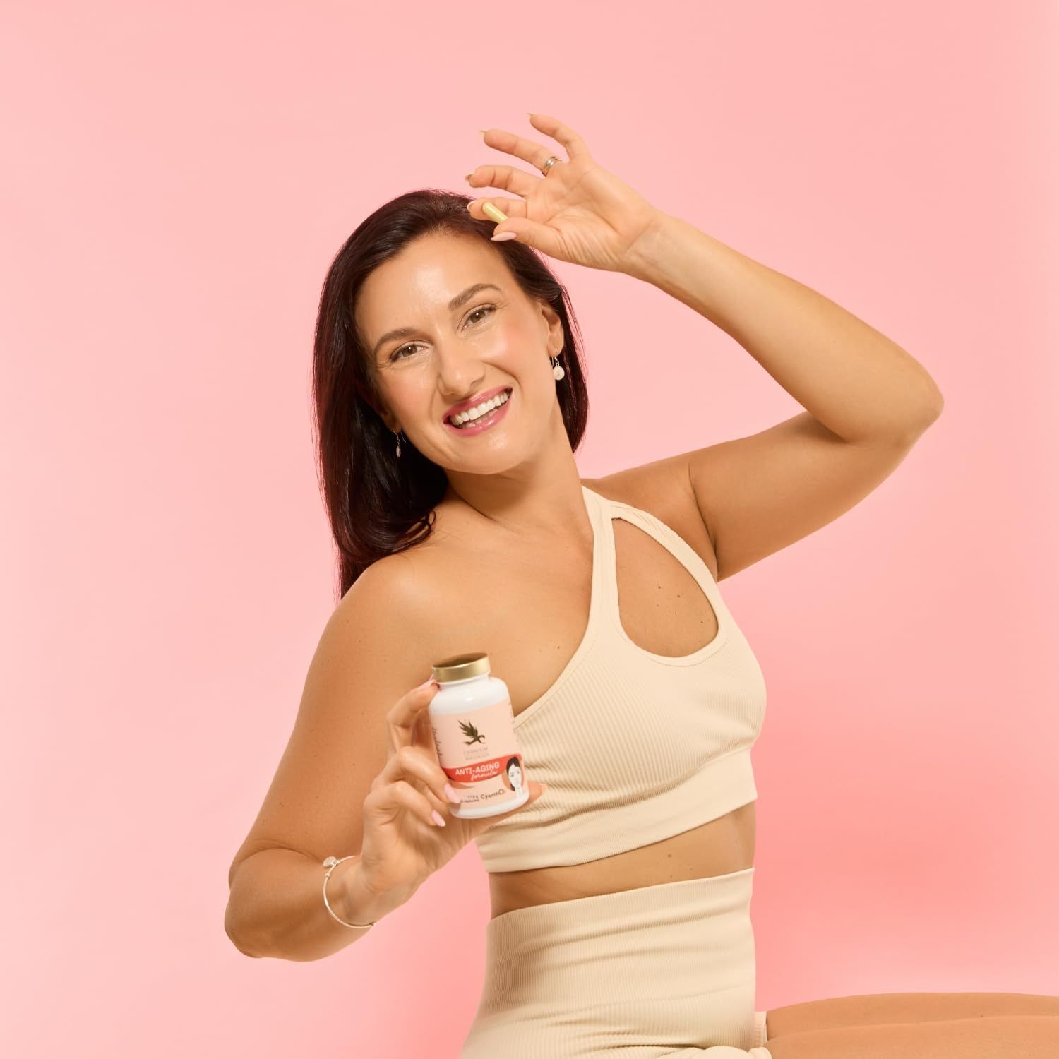 Donna tiene flacone con tappo dorato. Scritta: Anti-Aging formula. Donna sorridente.
