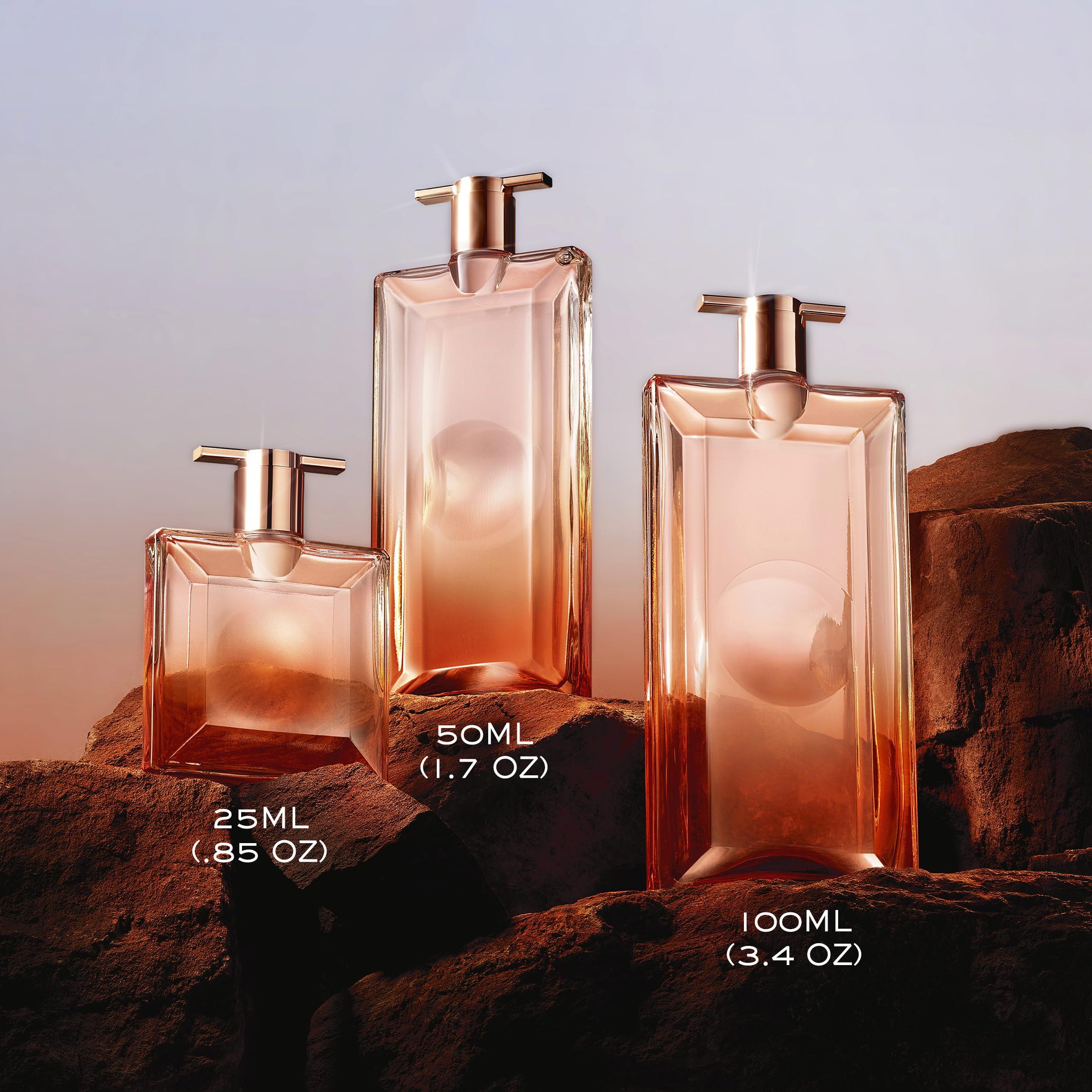 Tre flaconi di profumo in diverse dimensioni: 25ml, 50ml, 100ml. Nome del prodotto non visibile.