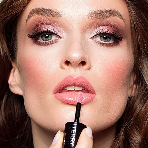 Donna applica By Terry Lip Expert Shine. Applicatore sulla bocca. Rossetto rosa, finitura lucida. Trucco.