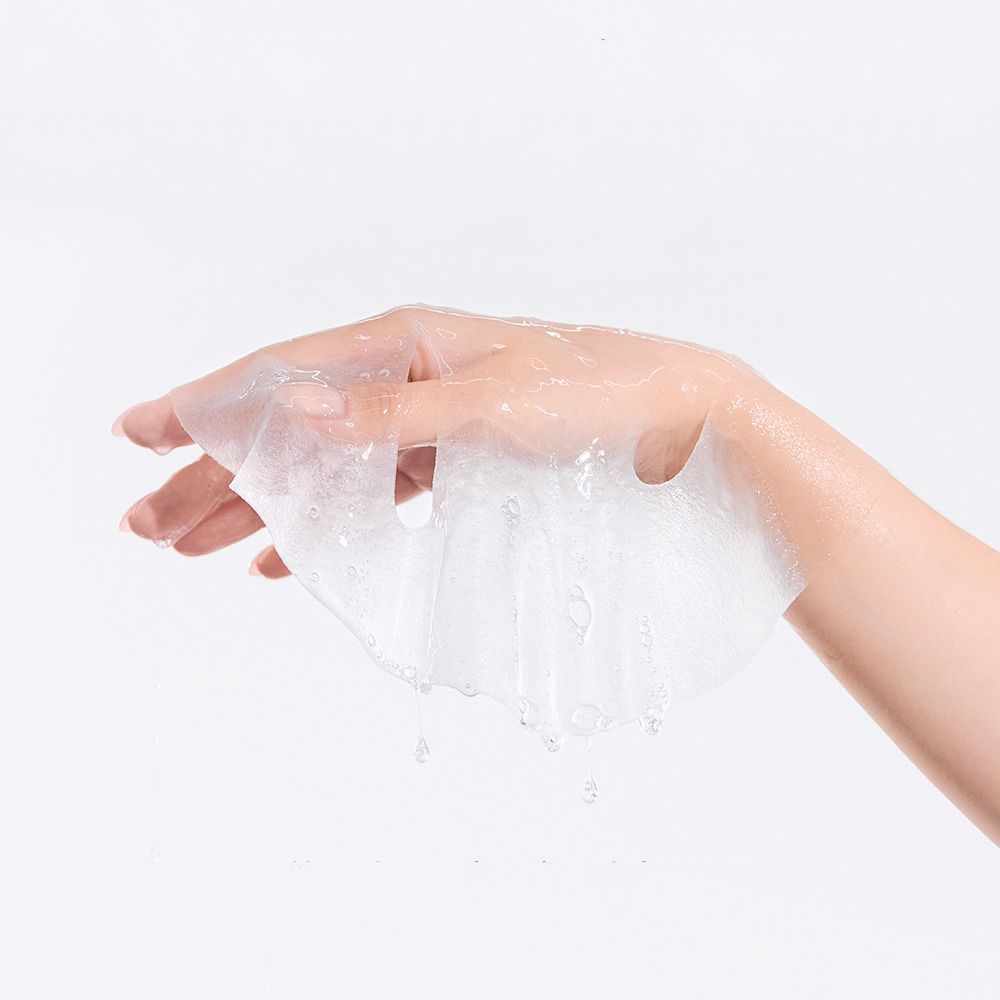 Una maschera in tessuto trasparente in una mano. La maschera è ricoperta di liquido.