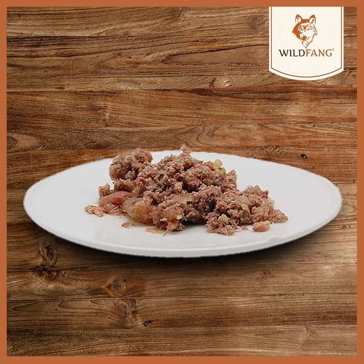 Piatto bianco con cibo. Consistenza: carne tritata grossolanamente. Sfondo: legno.