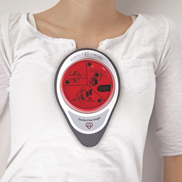 Cardio First Angel sul petto. Pulsante rosso con istruzioni, cornice bianca, schiuma grigia. Testo: Cardio First Angel.
