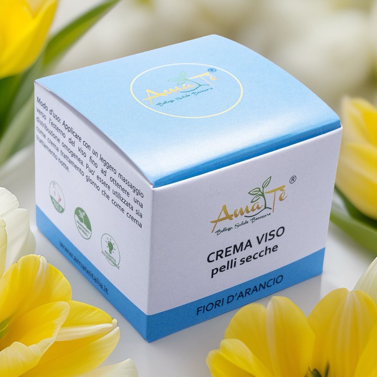 Confezione di Amatè Crema Viso Pelle Secca - Fiori d'Arancio. Scatola bianca e blu con informazioni e logo, con fiori gialli.
