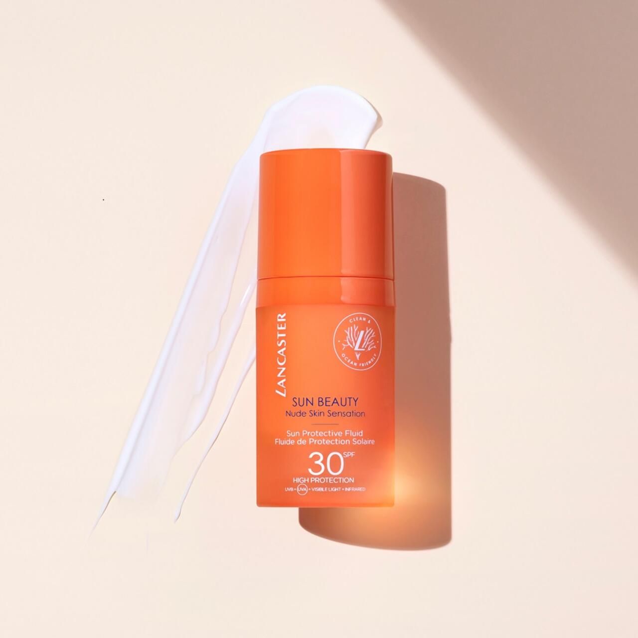 Flacone di crema solare con prodotto su sfondo chiaro. Scritta SUN BEAUTY, SPF 30, logo Lancaster.