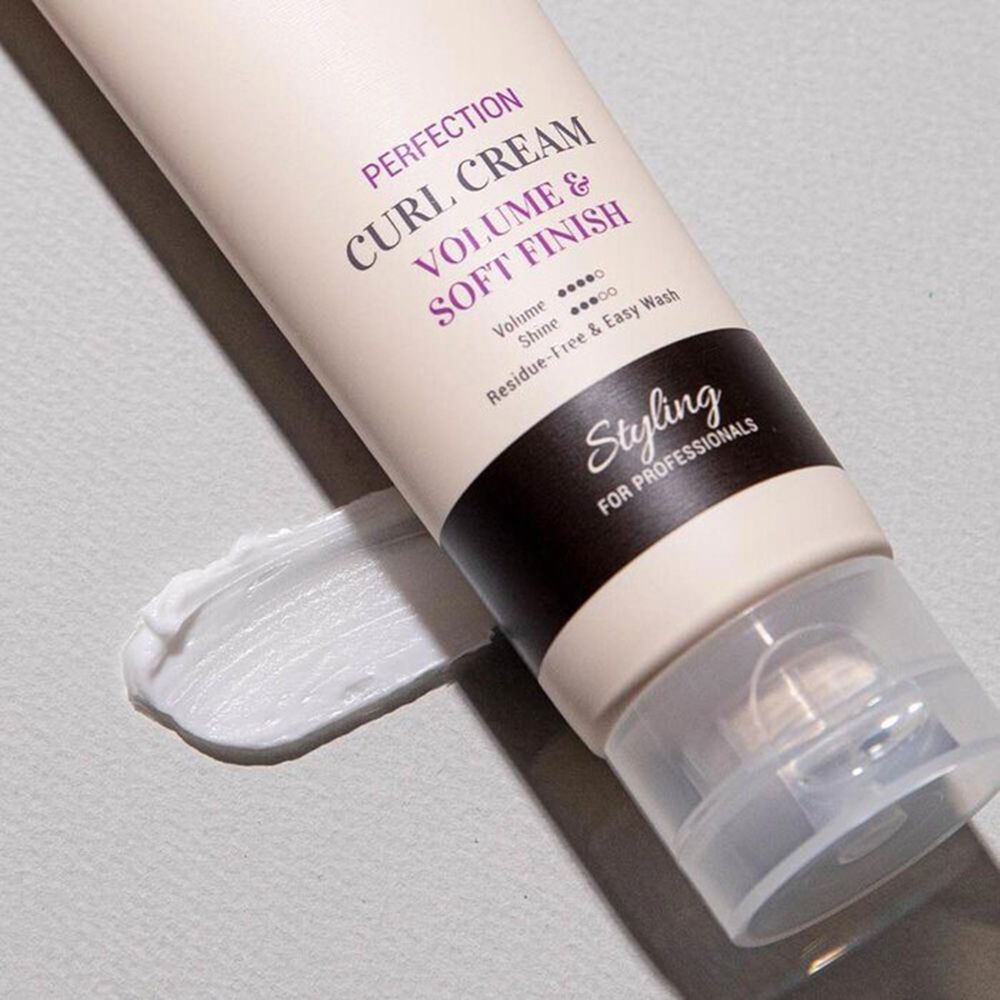 Primo piano di un tubo di crema e applicazione di crema. Testo: CURLY SHYLL, Perfection Curl Cream, Volume & Soft Finish. Testo Styling su striscia nera.