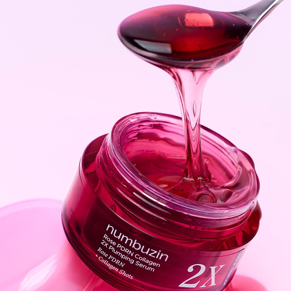 Un cucchiaio di siero NUMBUZIN Rose PDRN Collagen 2X Plumping Serum gocciola in un barattolo rosso aperto.