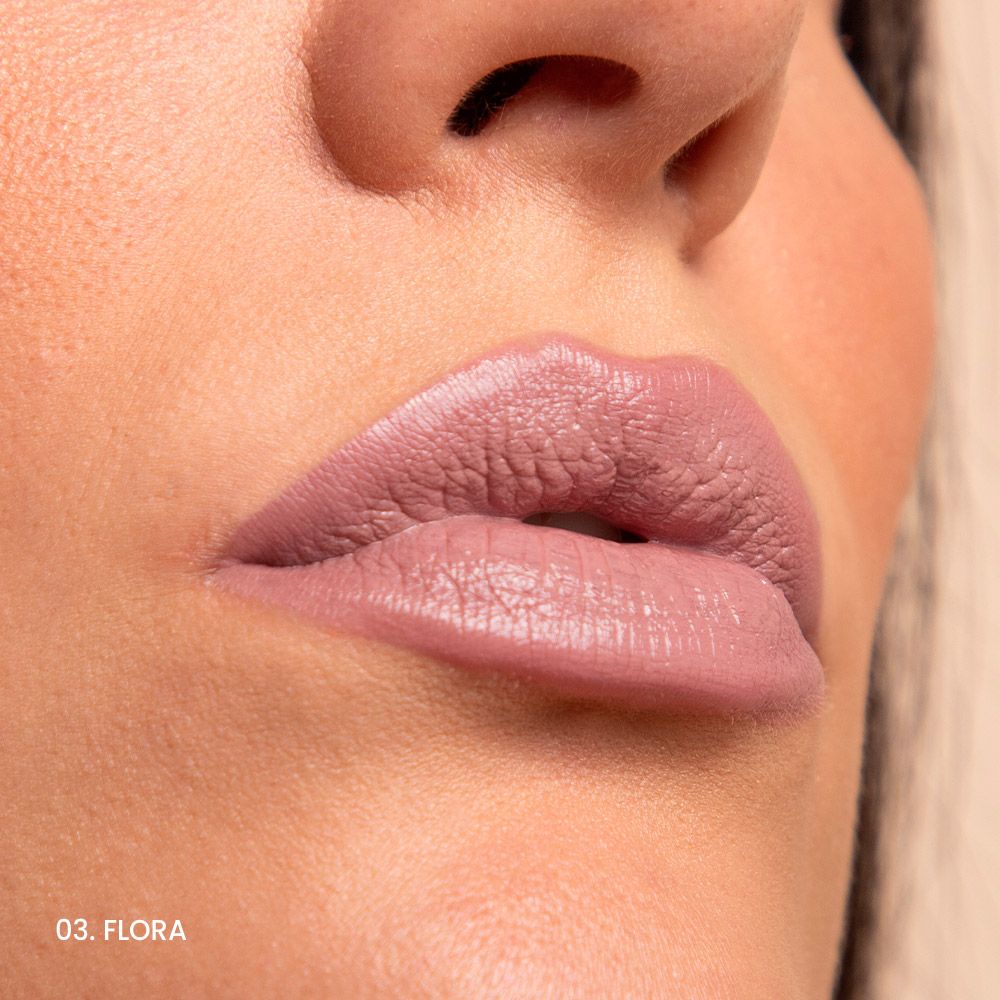 Primo piano di labbra con rossetto rosa. Sulle labbra inferiori è visibile la scritta 03. FLORA.