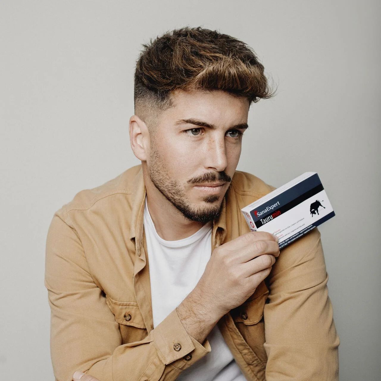 Uomo con scatola SanaExpert Tauro. Scatola con logo e scritta.