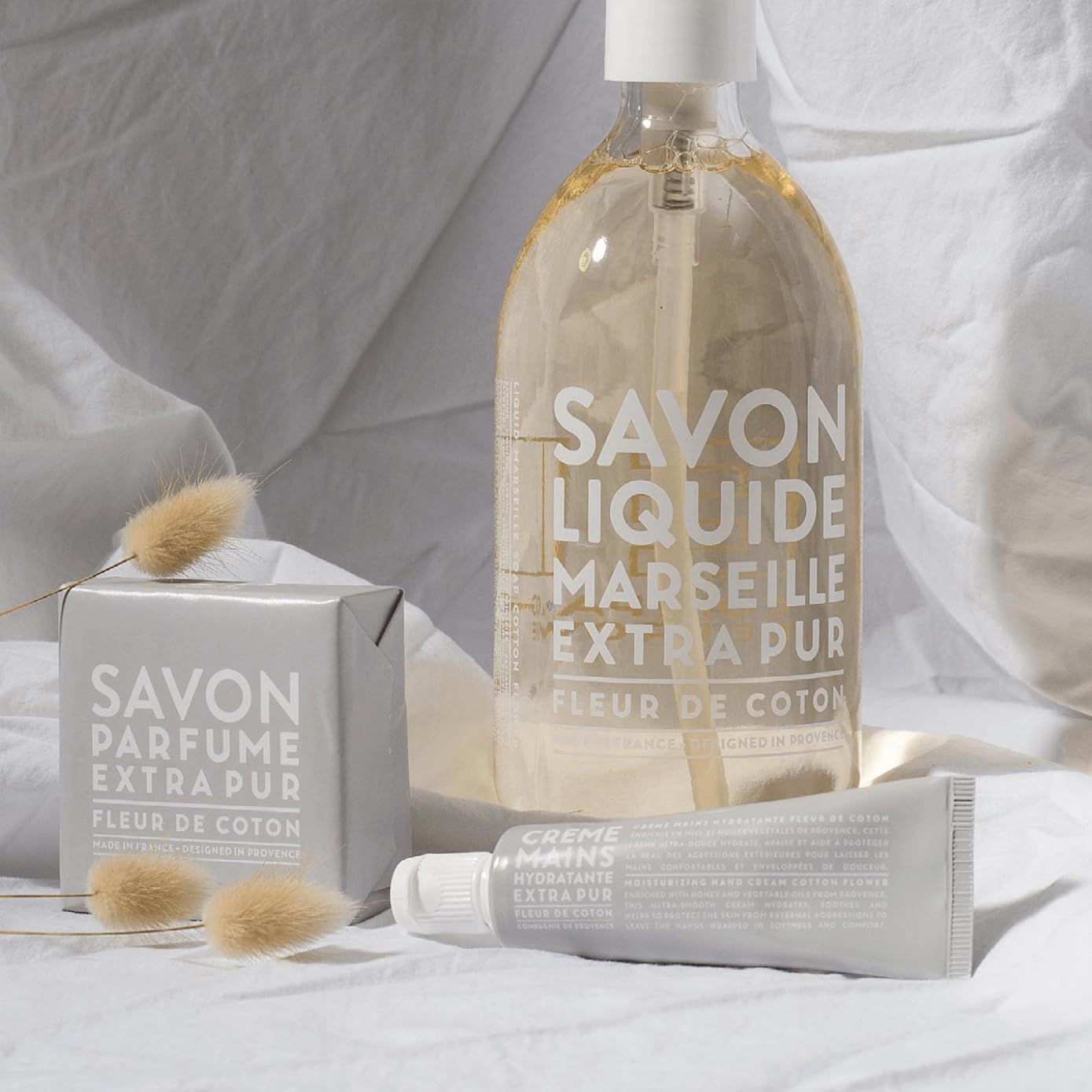 Sapone liquido e crema per le mani in confezioni neutre, decorate con erbe essiccate.