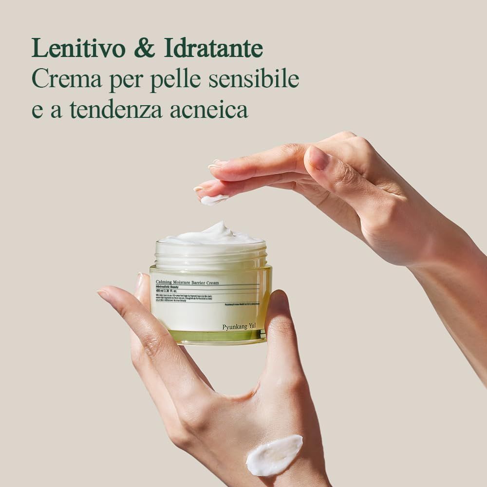 Mani che tengono un vasetto di crema. La crema viene applicata sulla mano. Testo: Lenitivo & Idratante. Crema per pelle sensibile e a tendenza acneica.