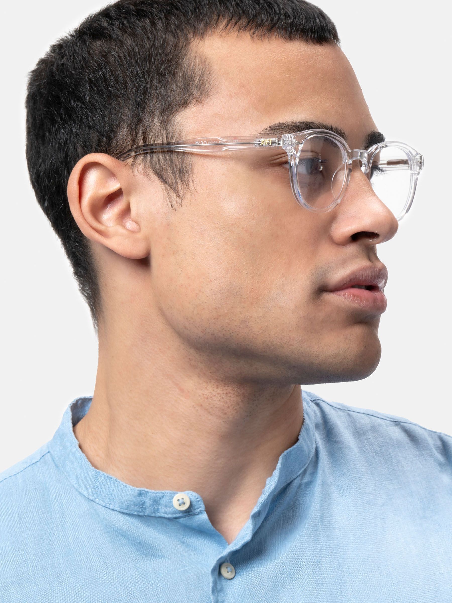 Uomo con camicia blu con occhiali trasparenti con lenti rotonde. "XFT" visibile sull'asta sinistra.