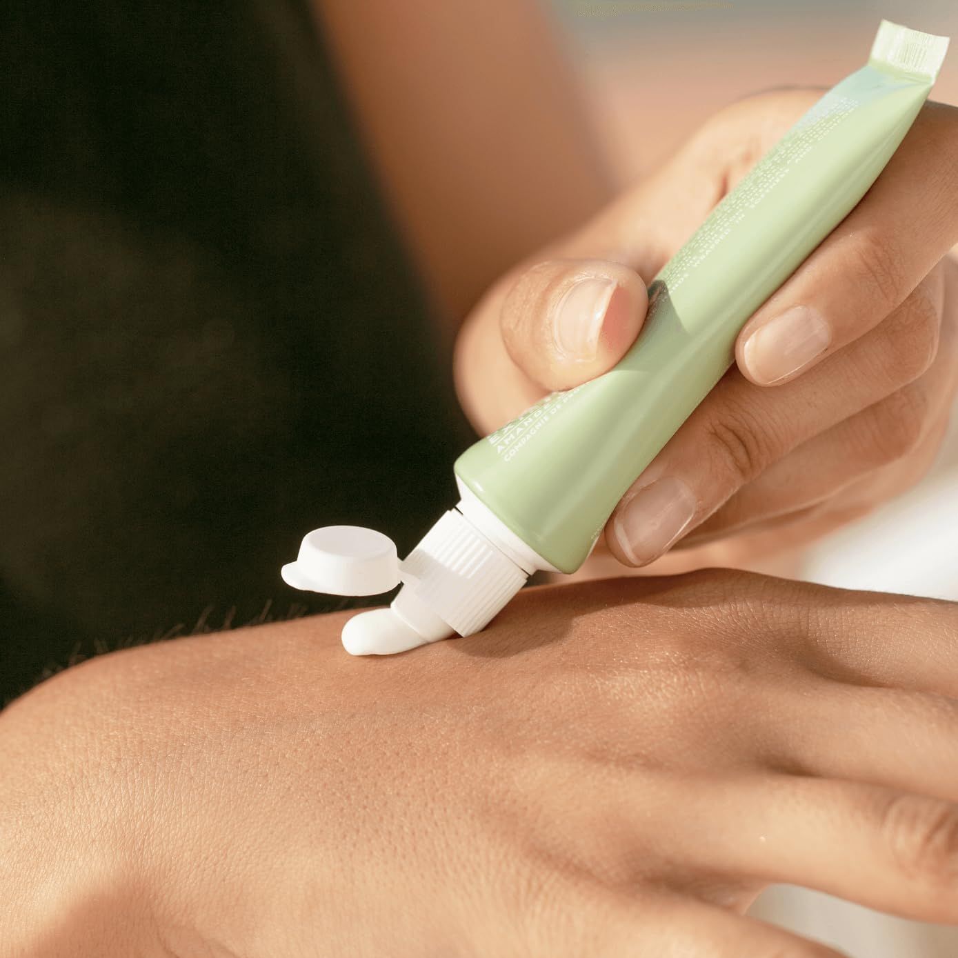 Un tubetto verde chiaro con unguento bianco viene applicato sulla pelle.