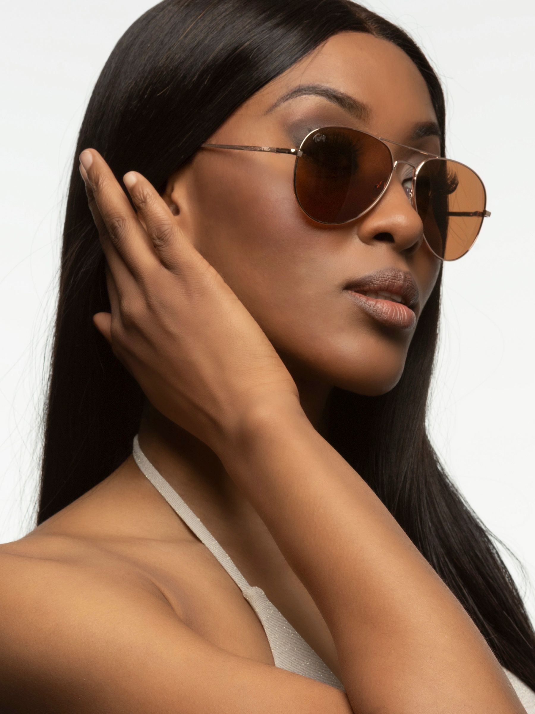 Donna con occhiali da sole Twig. Montatura dorata, lenti marroni. Primo piano.