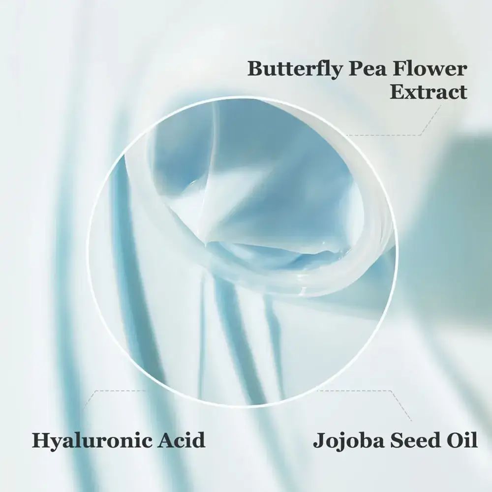 Primo piano della crema. Segni circolari con testo: Acido ialuronico, Olio di jojoba, Estratto di fiori di pisello farfalla.