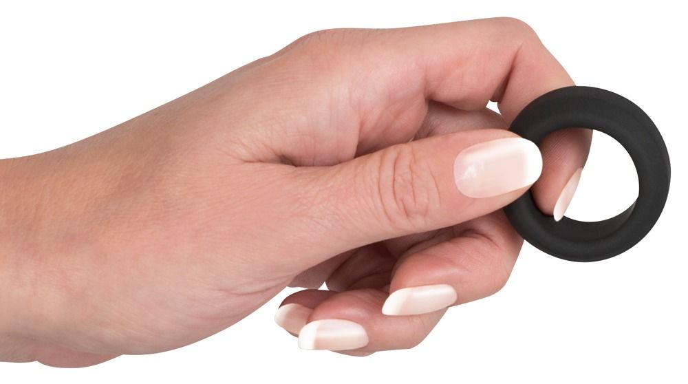 Mano che tiene un anello per pene nero e flessibile di forma rotonda.