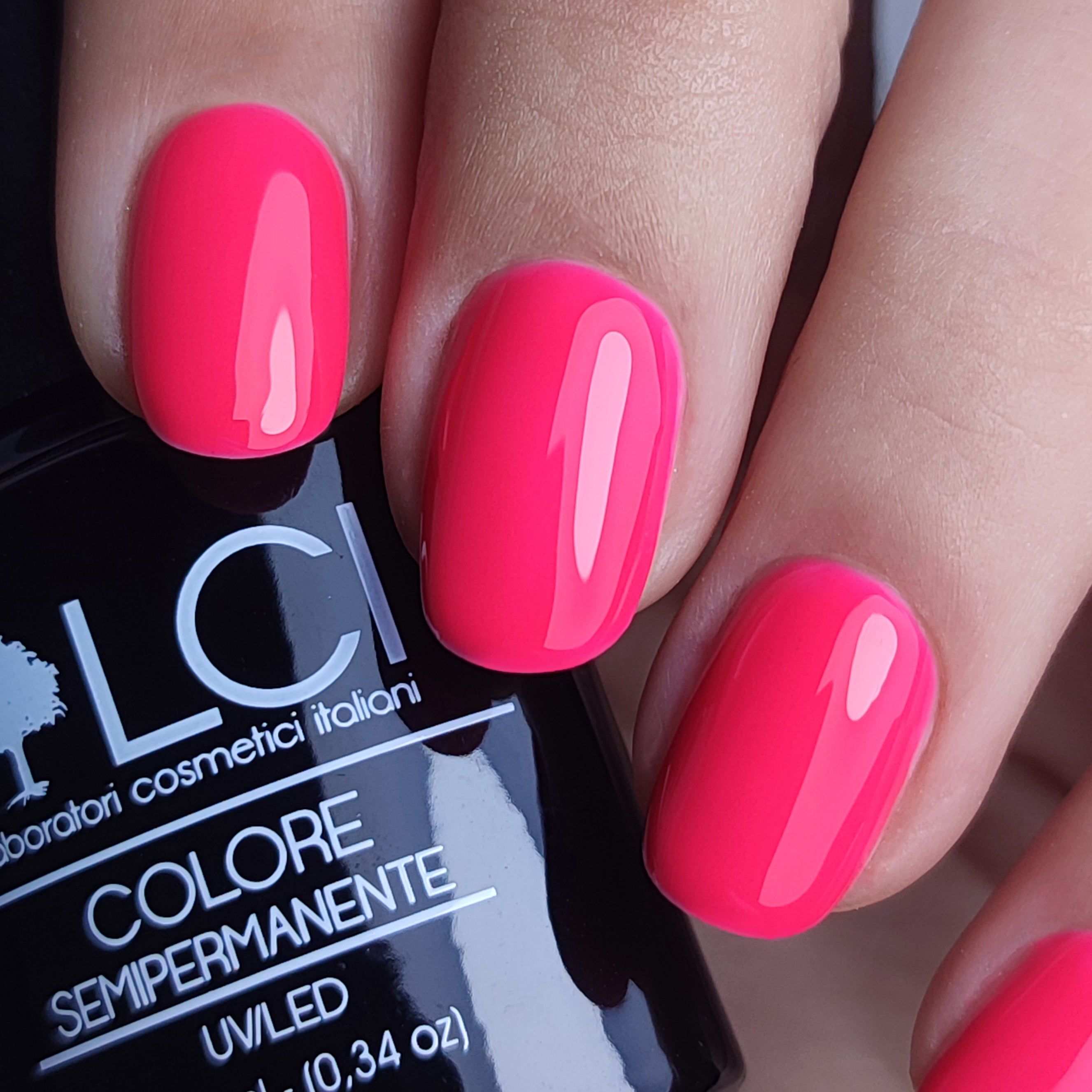 Mano con unghie smaltate rosa acceso. Flacone con scritta LCI, Colore Semipermanente, UVLED.