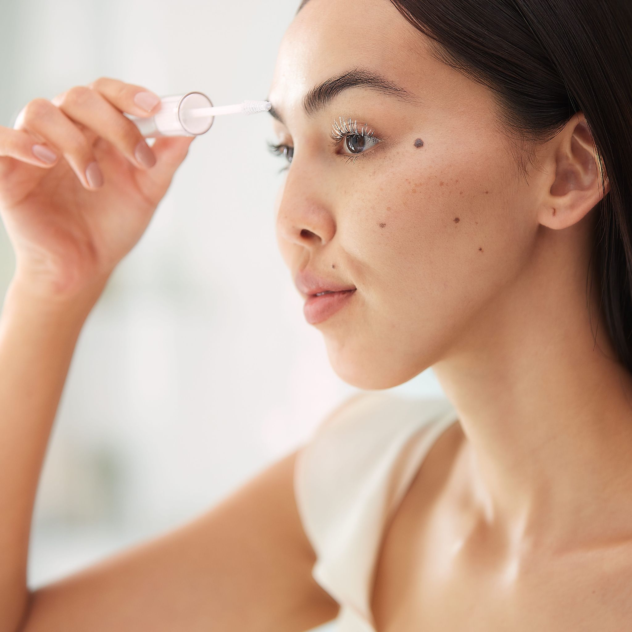 Donna applica una maschera per ciglia e sopracciglia con un applicatore.