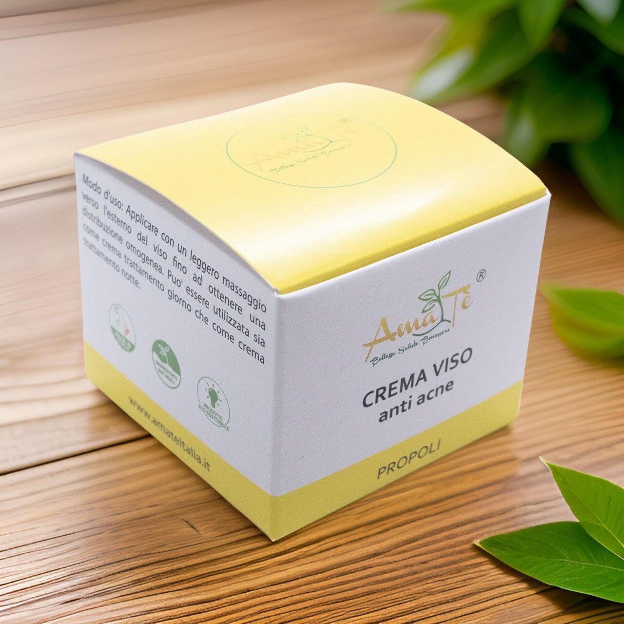 Scatola bianca e gialla su superficie in legno. Scritto: Crema viso anti acne, Propoli. Logo con foglie. Foglie verdi sullo sfondo.