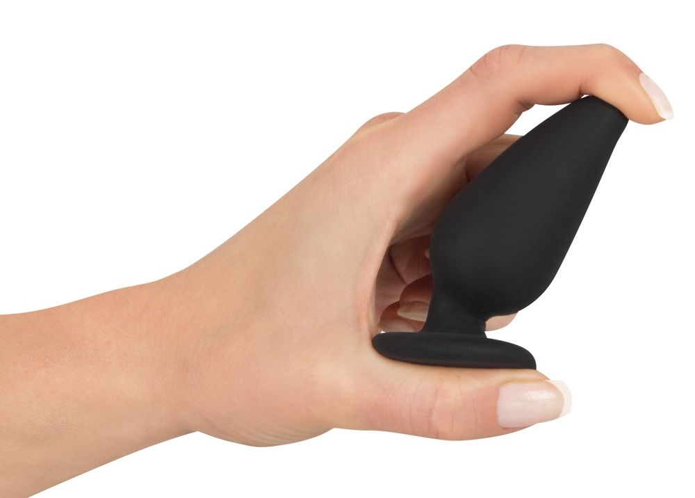 Plug anale nero con base, tenuto in mano. Punta conica, base rotonda.