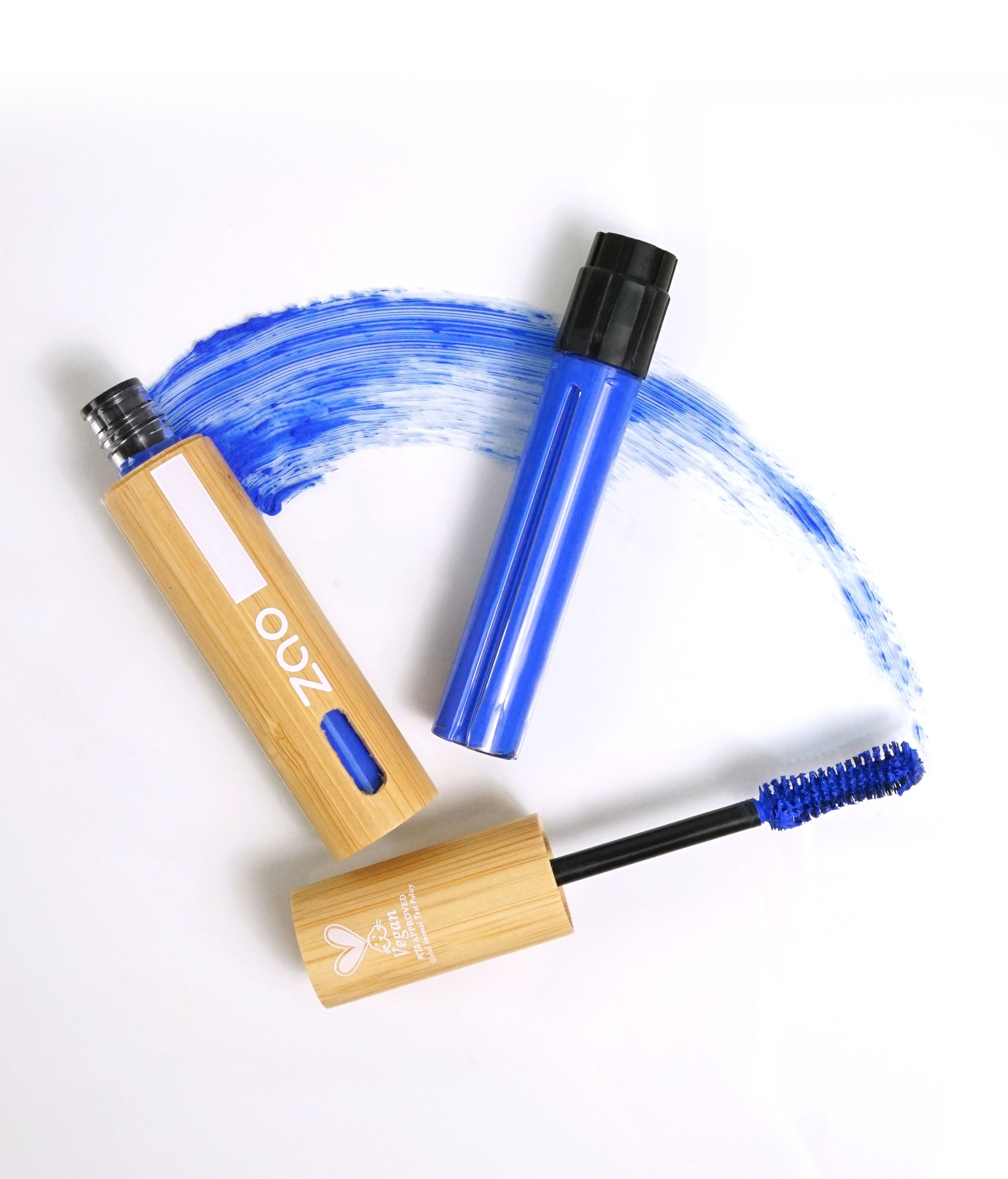 Due tubi di mascara in bambù, blu e nero. Un applicatore di mascara con spazzola blu. Logo vegano. Macchia di colore blu.